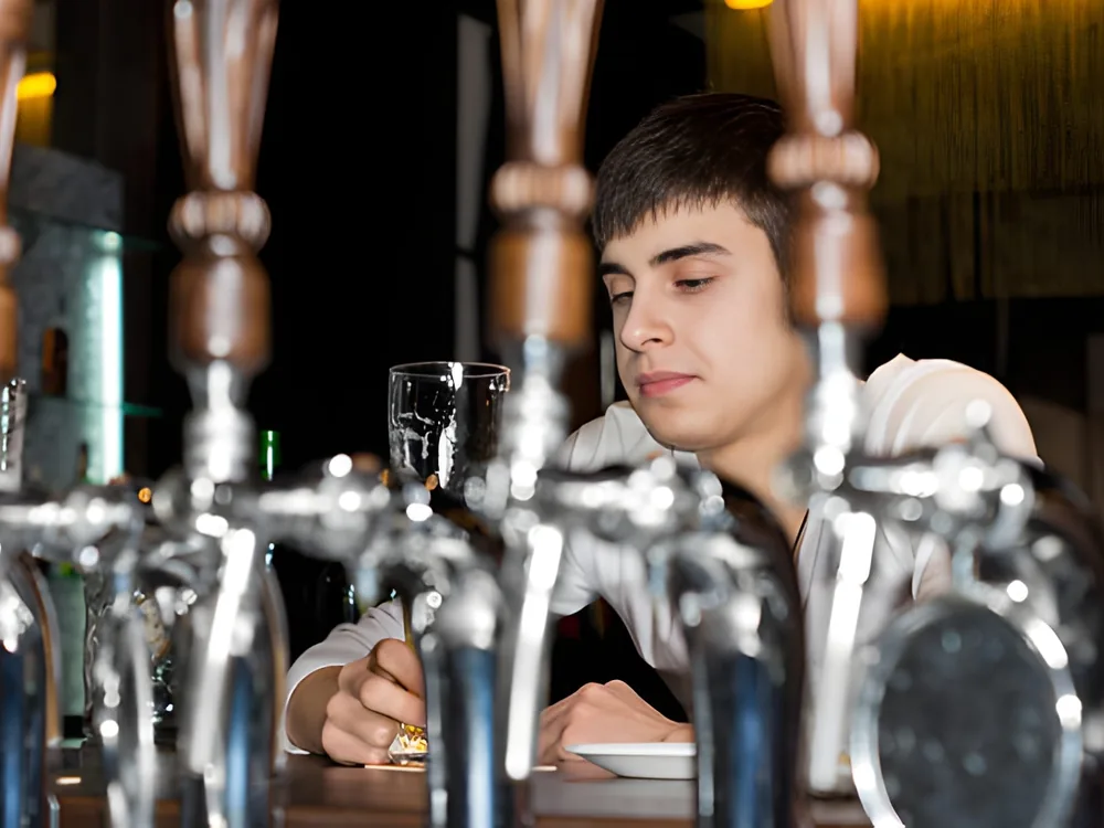 A bartender at a row of chrome draft faucets