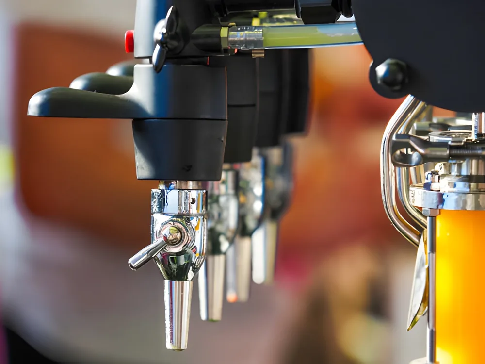 A row of chrome draft faucets in close-up, a glass filling at the end