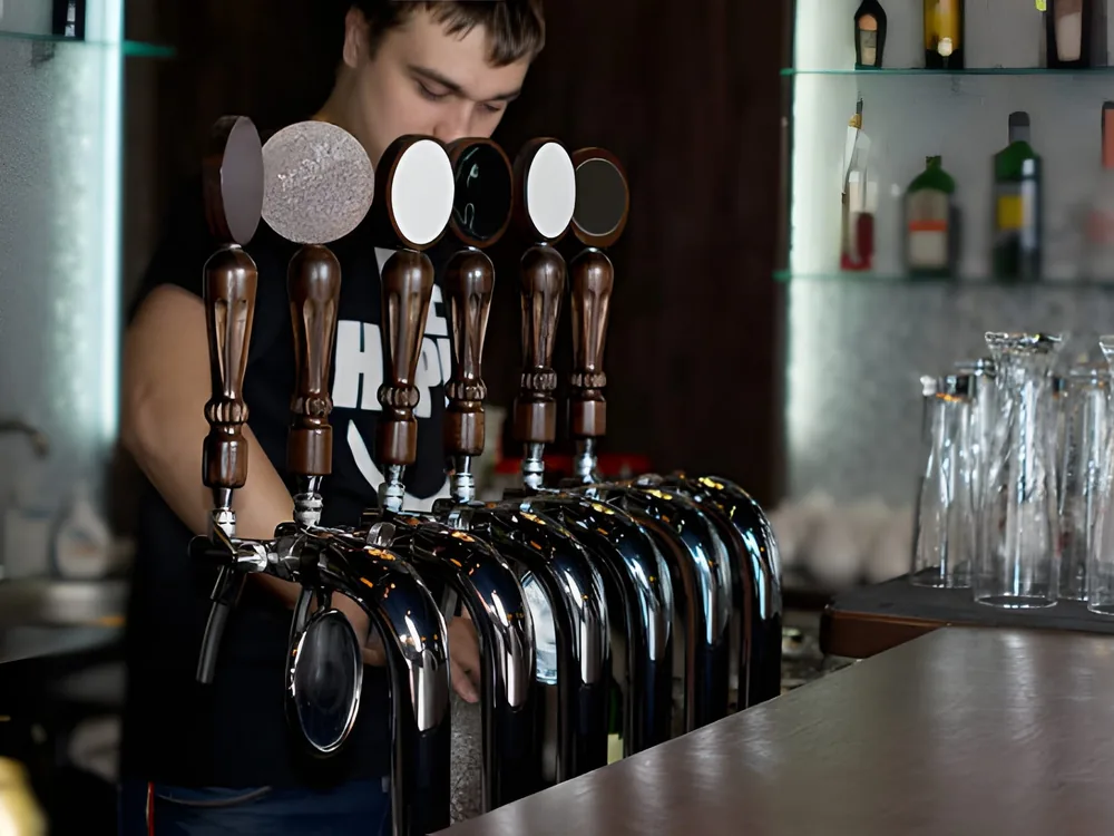 A bartender behind a row of draft tap handles