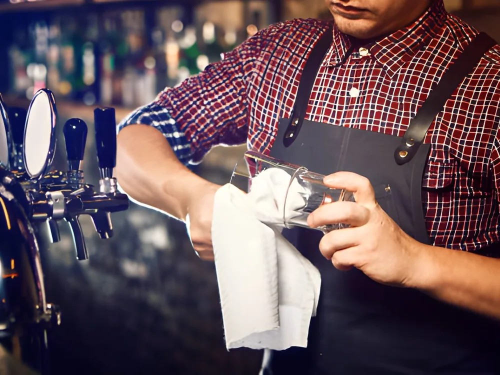 A towel polishing the faucets of a bank of draft taps