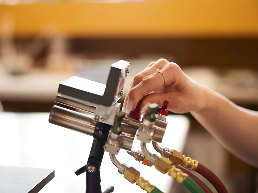 Hands working on a stainless steel draft tower with gas lines behind it